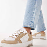 Woman wearing the Nubikk Buxton Basket sand sneakers with cropped blue jeans, street-style shot.