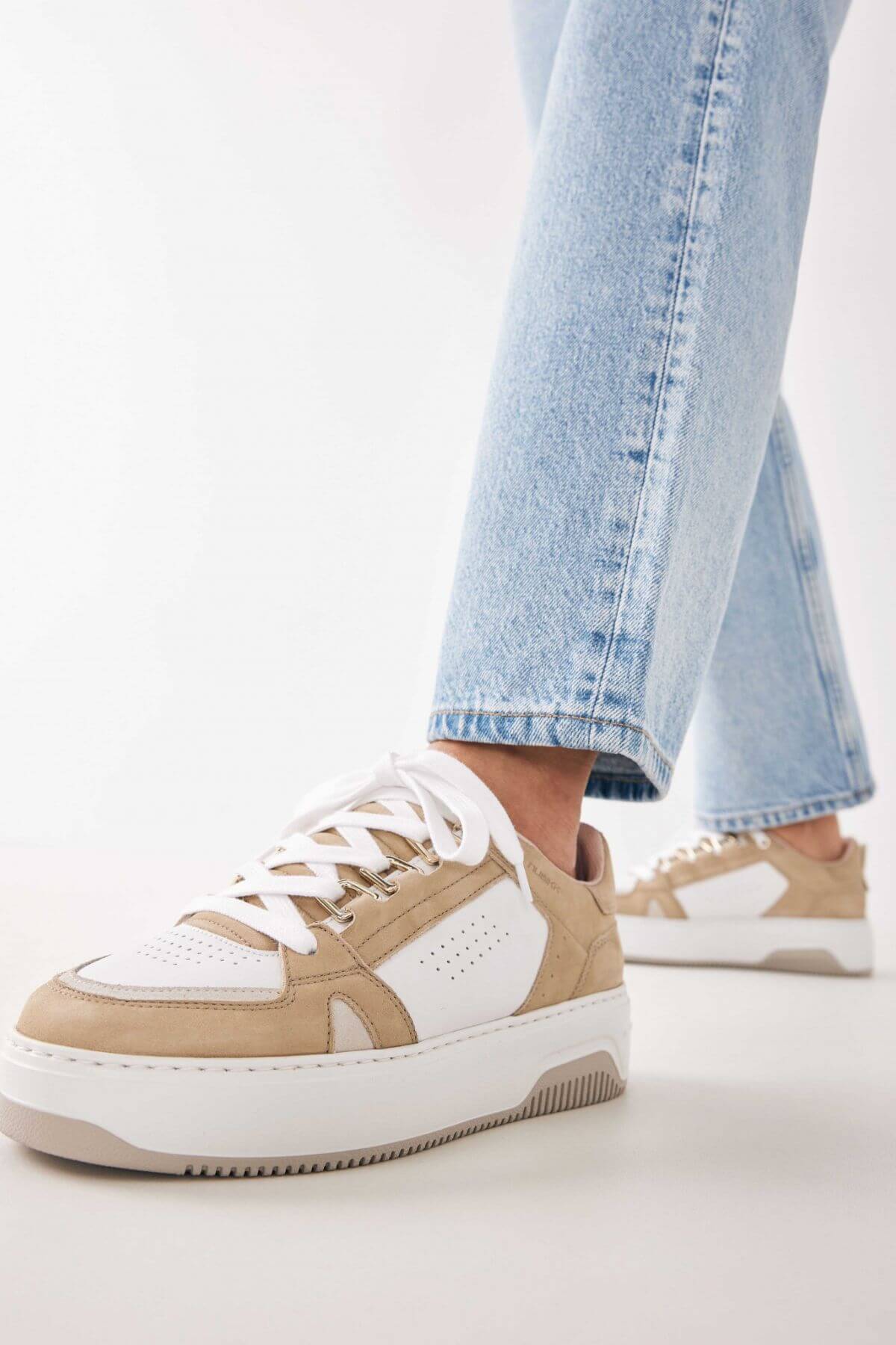 Woman wearing the Nubikk Buxton Basket sand sneakers with cropped blue jeans, street-style shot.