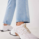 Woman wearing the Nubikk Ross Trek white sneakers with cropped blue jeans, street-style shot.
