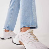 Woman wearing the Nubikk Ross Trek white sneakers with cropped blue jeans, street-style shot.
