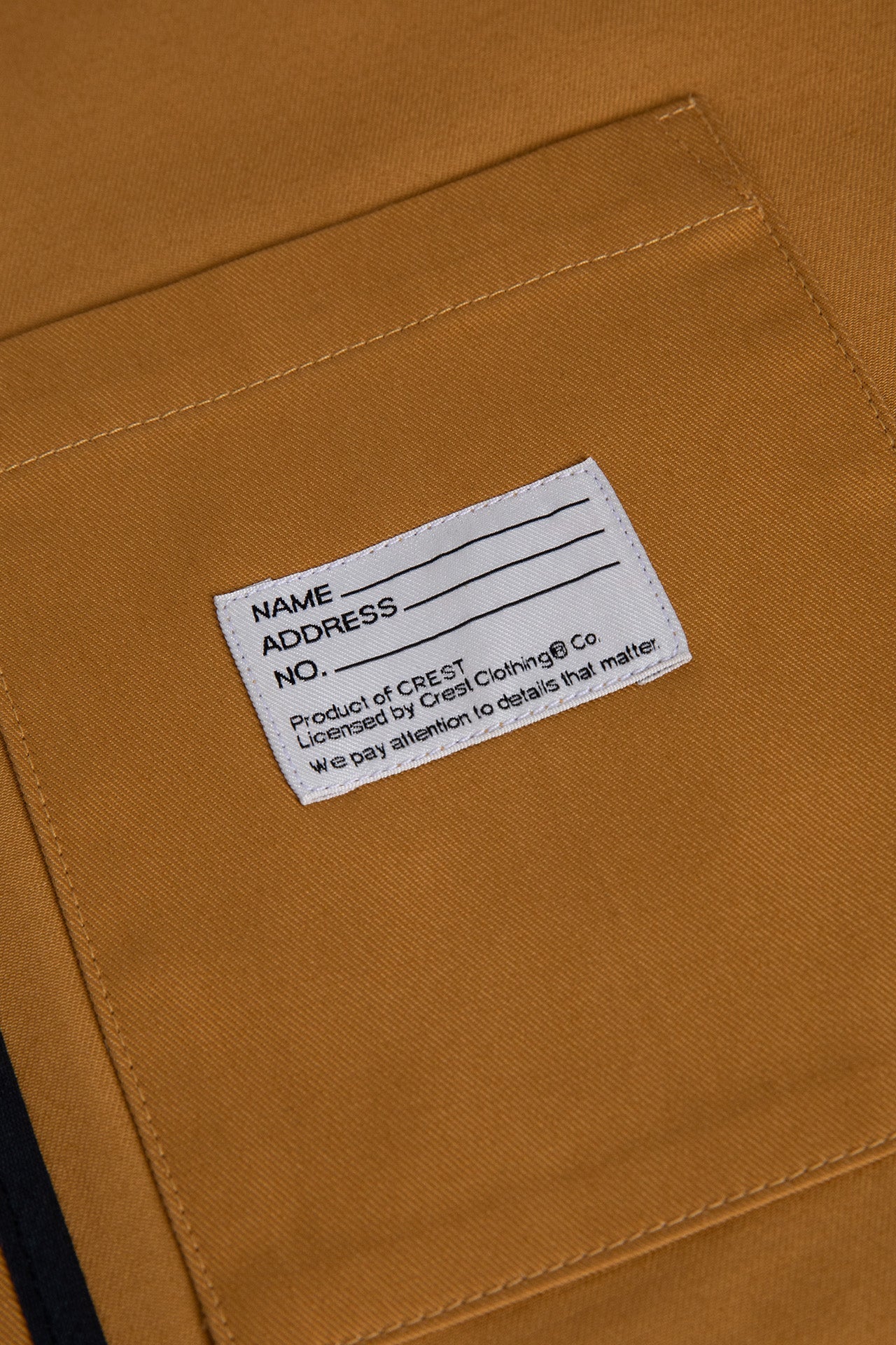 Inside patch pocket of the Mustard Yellow Patch Lightweight Men's Jacket, featuring CREST's signature Name Patch label.