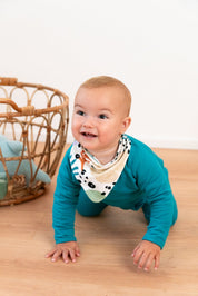 Ababy crawling on the floor with a bandana around his neck