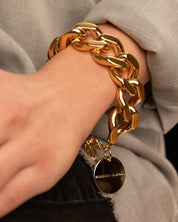 Woman wearing Vanessa Baroni's elegant gold flat chain bracelet, showcasing a modern design with chunky links and a secure gold clasp.